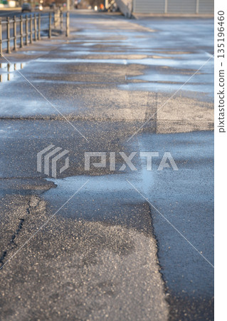 Deicing chemicals on asphalt in winter. Salt grains on icy sidewalk paving slab with technical salt Deicing chemicals on asphalt in winter. Salt grains on icy sidewalk paving slab with technical salt 135196460
