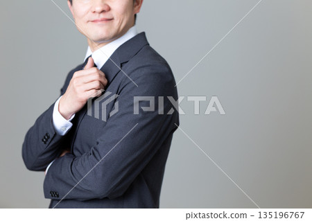 A middle-aged male businessman in a suit with his arms folded A middle-aged male businessman in a suit with his arms folded 135196767