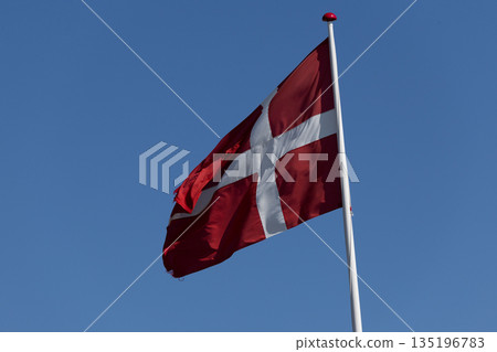 Danish Flag Flutters Majestically Against Clear Blue Sky Background Danish Flag Flutters Majestically Against Clear Blue Sky Background 135196783