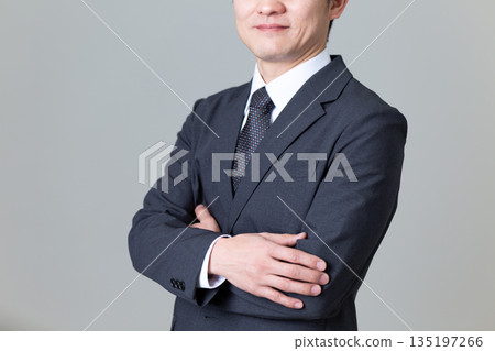 A middle-aged male businessman in a suit with his arms folded 135197266