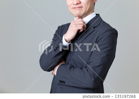 A middle-aged male businessman in a suit with his arms folded 135197268