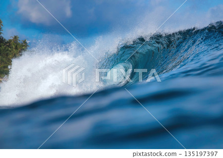 Clear Sky And Sharp Sunlight Illuminate Massive Turquoise Coastal Wave In Motion 135197397
