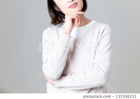 一位身穿休閒針織衫的中年婦女正在思考 一位身穿休閒針織衫的中年婦女正在思考 135198151