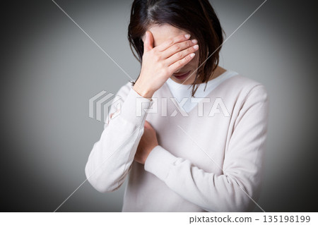 A middle-aged woman in casual knitwear looking worried A middle-aged woman in casual knitwear looking worried 135198199