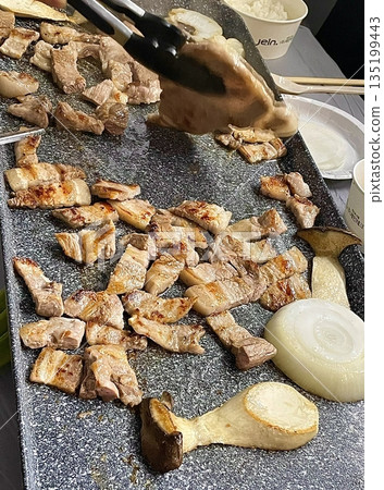 Grilled samgyeopsal, showcasing thick slices of pork belly sizzling on the grill. A popular Korean barbecue dish, capturing the essence of a delicious dining experience. Grilled samgyeopsal, showcasing thick slices of pork belly sizzling on the grill. A popular Korean barbecue dish, capturing the essence of a delicious dining experience. 135199443
