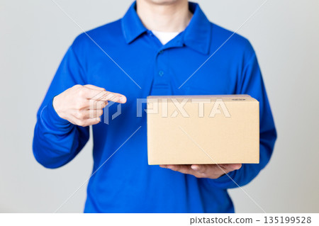A man in the logistics and transportation industry holding a cardboard box 135199528
