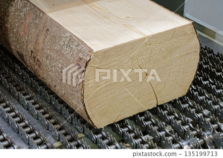 Partially processed log on the conveyor of a woodworking machine Partially processed log on the conveyor of a woodworking machine 135199713