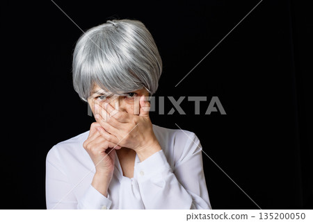 A white-haired senior woman wearing a blouse glaring at someone with her mouth closed A white-haired senior woman wearing a blouse glaring at someone with her mouth closed 135200050