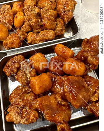 Crispy Korean fried chicken, perfectly glazed with a sweet and spicy sauce. Ideal for food photography and menus, showcasing the irresistible crunch and flavor of this beloved dish. 135200684
