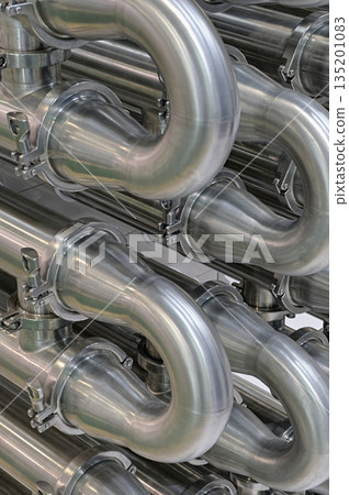 A lot of shiny curved stainless steel pipes of industrial equipment cooling system A lot of shiny curved stainless steel pipes of industrial equipment cooling system 135201083