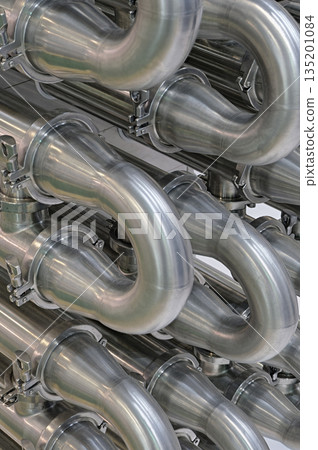 A lot of shiny curved stainless steel pipes of industrial equipment cooling system A lot of shiny curved stainless steel pipes of industrial equipment cooling system 135201084