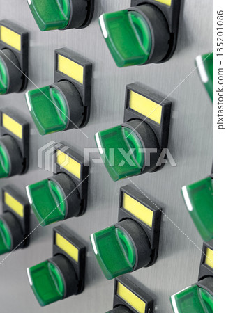 A lot of green electric switches with yellow labels on a brushed metal control panel 135201086