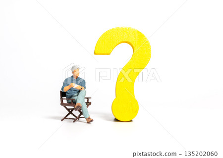 Miniature Man Sitting Beside Yellow Question Mark 135202060