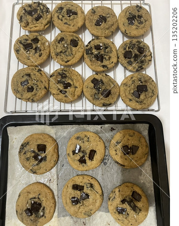 Freshly baked cookies with a golden-brown finish and chocolate chips. Perfectly crisp on the edges with a soft center, offering a delicious, comforting treat for any occasion. 135202206