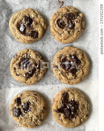 Freshly baked cookies with a golden-brown finish and chocolate chips. Perfectly crisp on the edges with a soft center, offering a delicious, comforting treat for any occasion. Freshly baked cookies with a golden-brown finish and chocolate chips. Perfectly crisp on the edges with a soft center, offering a delicious, comforting treat for any occasion. 135202209