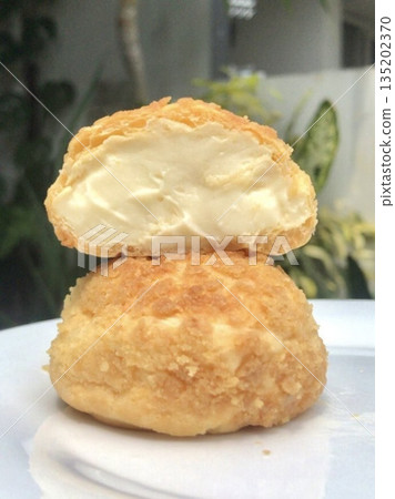 Golden choux au craquelin, featuring crisp pastry shells topped with a delicate, crumbly layer and filled with luscious cream. A delightful treat perfect for any indulgent moment. Golden choux au craquelin, featuring crisp pastry shells topped with a delicate, crumbly layer and filled with luscious cream. A delightful treat perfect for any indulgent moment. 135202370