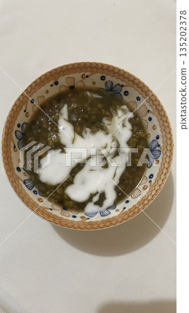 Bubur kacang hijau made with mung beans cooked in sweet coconut milk, served warm with a creamy texture and rich flavor, often enjoyed as a comforting traditional Indonesian dessert or snack Bubur kacang hijau made with mung beans cooked in sweet coconut milk, served warm with a creamy texture and rich flavor, often enjoyed as a comforting traditional Indonesian dessert or snack 135202378