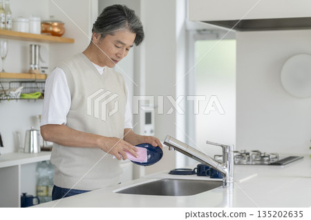 一位五十多歲的男子正在洗碗。 135202635
