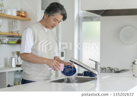 A man in his 50s washing dishes at the kitchen sink 135202637