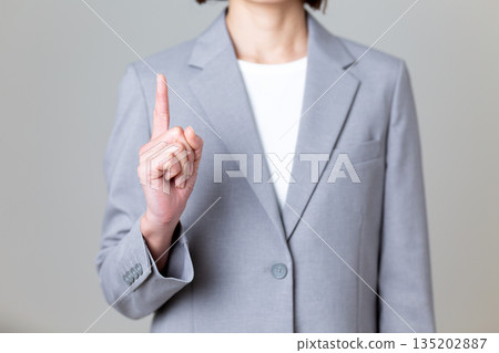 A middle-aged female business woman in a gray suit pointing up A middle-aged female business woman in a gray suit pointing up 135202887