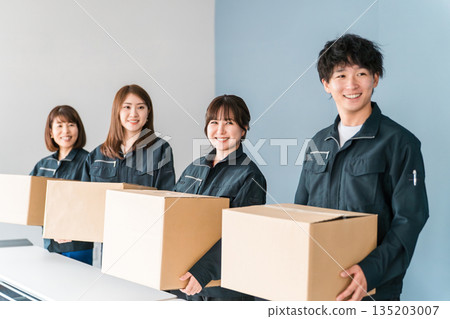 Male and female staff in the transportation and delivery industry wearing work clothes carrying cardboard packages 135203007