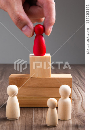 Hand placing red leader peg on wooden pedestal Hand placing red leader peg on wooden pedestal 135203161