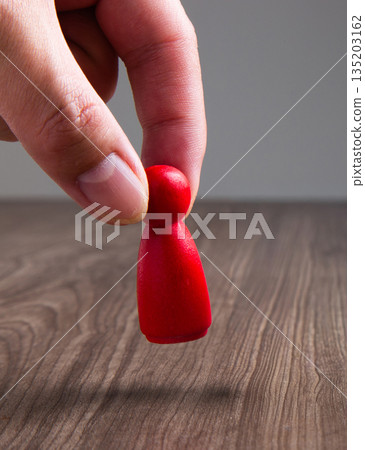 Hand moving red wooden game piece Hand moving red wooden game piece 135203162