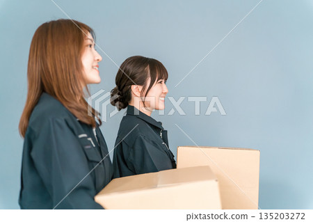 A woman working as a light worker, transporter, logistics, home delivery, distribution, delivery, or courier, holding a cardboard box 135203272