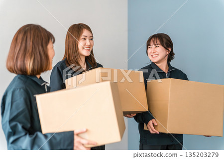 A woman working as a light worker, transporter, logistics, home delivery, distribution, delivery, or courier, holding a cardboard box A woman working as a light worker, transporter, logistics, home delivery, distribution, delivery, or courier, holding a cardboard box 135203279