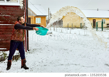 Spilling dirty water on snow in yard after wet cleaning inside, mature man spills washbasin with sharp motion, water forms arc. Spilling dirty water on snow in yard after wet cleaning inside, mature man spills washbasin with sharp motion, water forms arc. 135203536