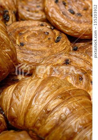 Various types of traditional pastries made from puff pastry - croissants and buns with raisins 135203912