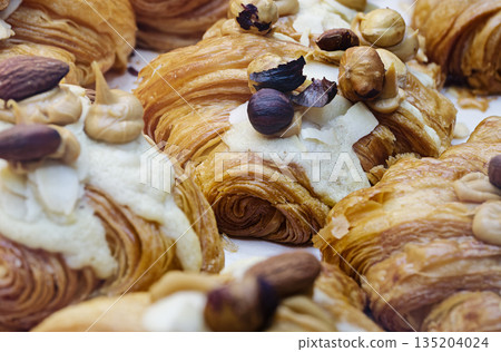 Group of fresh baked croissants, with topping of butter cream, caramel and roasted hazelnuts Group of fresh baked croissants, with topping of butter cream, caramel and roasted hazelnuts 135204024