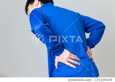 一名身穿藍色工作服的中年男子，在物流運輸業工作，他正遭受背痛的困擾。 135204076