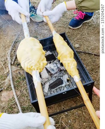 Child baking Baumkuchen using a bamboo pole Child baking Baumkuchen using a bamboo pole 135204267