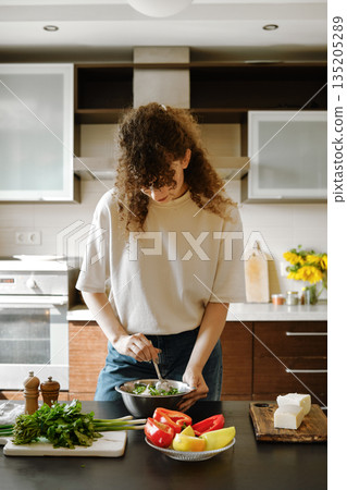 Woman mix grated goat cheese and chopped cilantro into a bowl Woman mix grated goat cheese and chopped cilantro into a bowl 135205289
