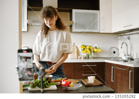 Joyful woman preparing food in the kitchen and recording video recipe 135205292