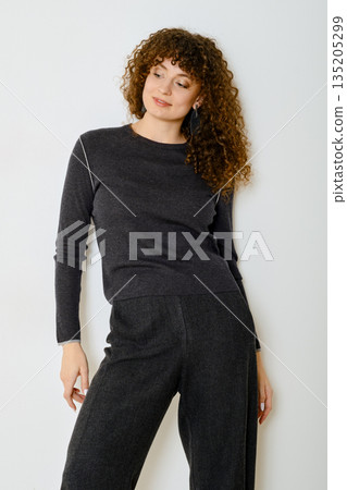 Model poses in casual outfit showcasing soft fabric and stylish design in indoor setting Model poses in casual outfit showcasing soft fabric and stylish design in indoor setting 135205299