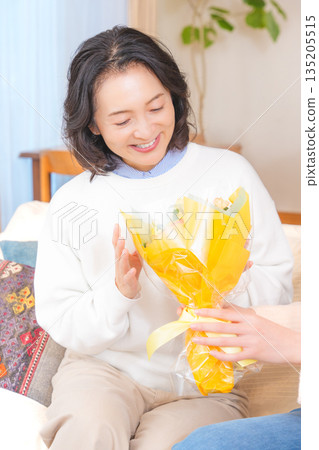 Daughter giving a present to her mother Daughter giving a present to her mother 135205515