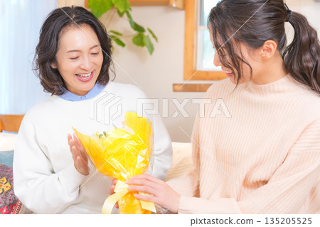 Daughter giving a present to her mother Daughter giving a present to her mother 135205525