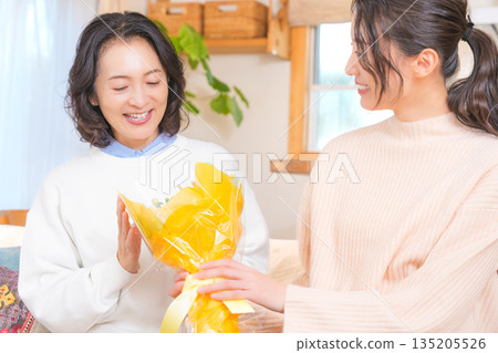 Daughter giving a present to her mother Daughter giving a present to her mother 135205526