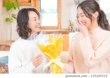 Daughter giving a present to her mother Daughter giving a present to her mother 135205533