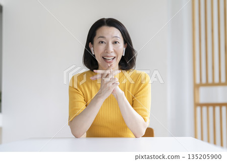 A woman in her 50s wearing earphones and smiling while looking at the camera A woman in her 50s wearing earphones and smiling while looking at the camera 135205900