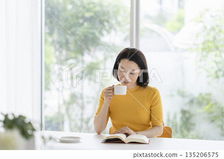 A woman in her fifties reading a book A woman in her fifties reading a book 135206575