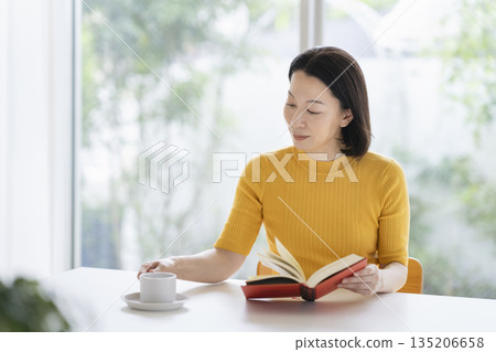 A woman in her fifties reading a book A woman in her fifties reading a book 135206658