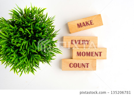 wooden blocks show the phrase make every moment count next to a bright green potted plant on a white surface, encouraging living a life full of purpose wooden blocks show the phrase make every moment count next to a bright green potted plant on a white surface, encouraging living a life full of purpose 135206781
