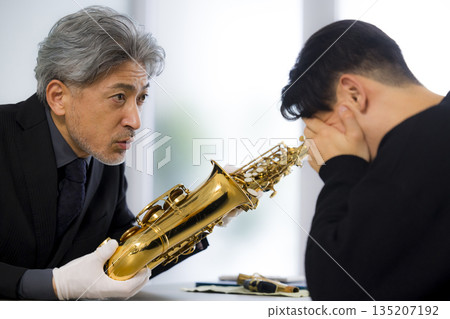 一名男子正在鑑定一支薩克斯風 一名男子正在鑑定一支薩克斯風 135207192