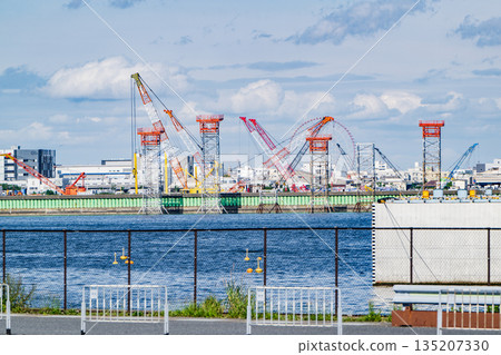 Industrial area along Tokyo Bay, construction cranes and cloudy sky Industrial area along Tokyo Bay, construction cranes and cloudy sky 135207330