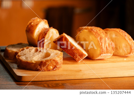 Pre-cut baguette (French bread) on a cutting board 135207444