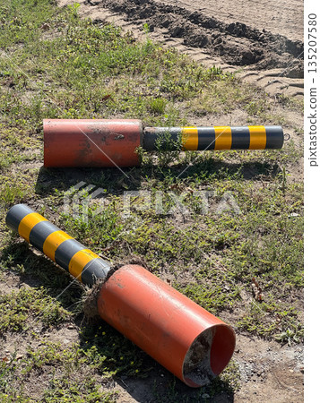 Removed traffic bollards lying on the ground near sidewalk 135207580