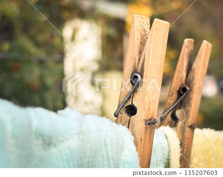 Closeup of wooden clothespins on a laundry line outdoors. Closeup of wooden clothespins on a laundry line outdoors. 135207603